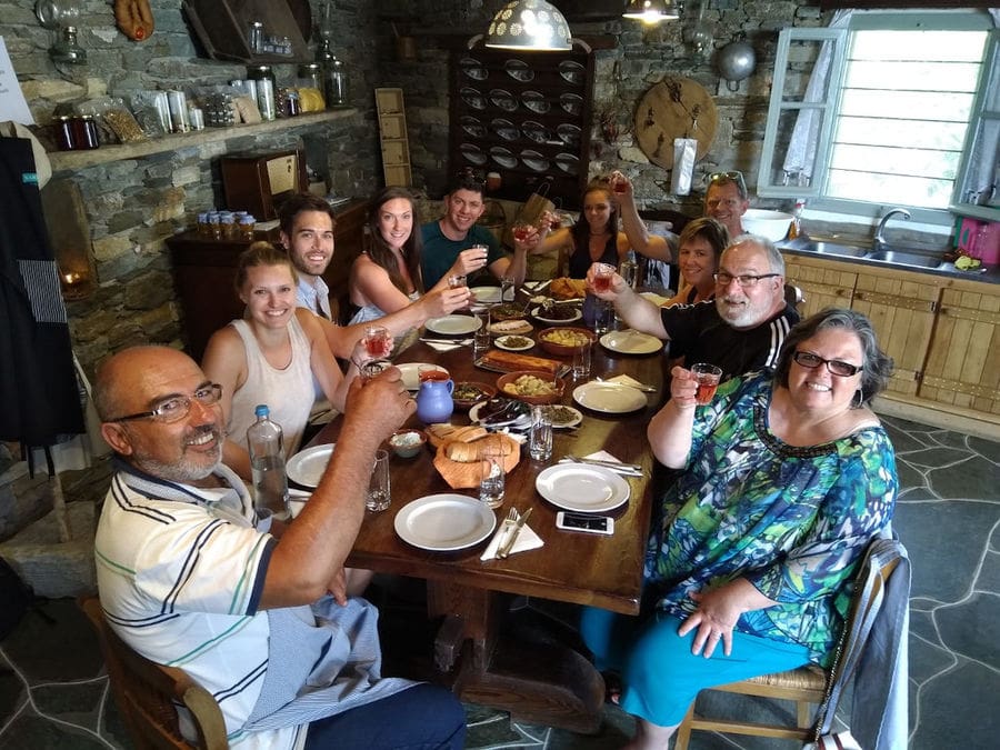 tourists smiling at the camera and holding glasses of wine for 'cheers' and eating aperitifs at 'Narlis Farm'